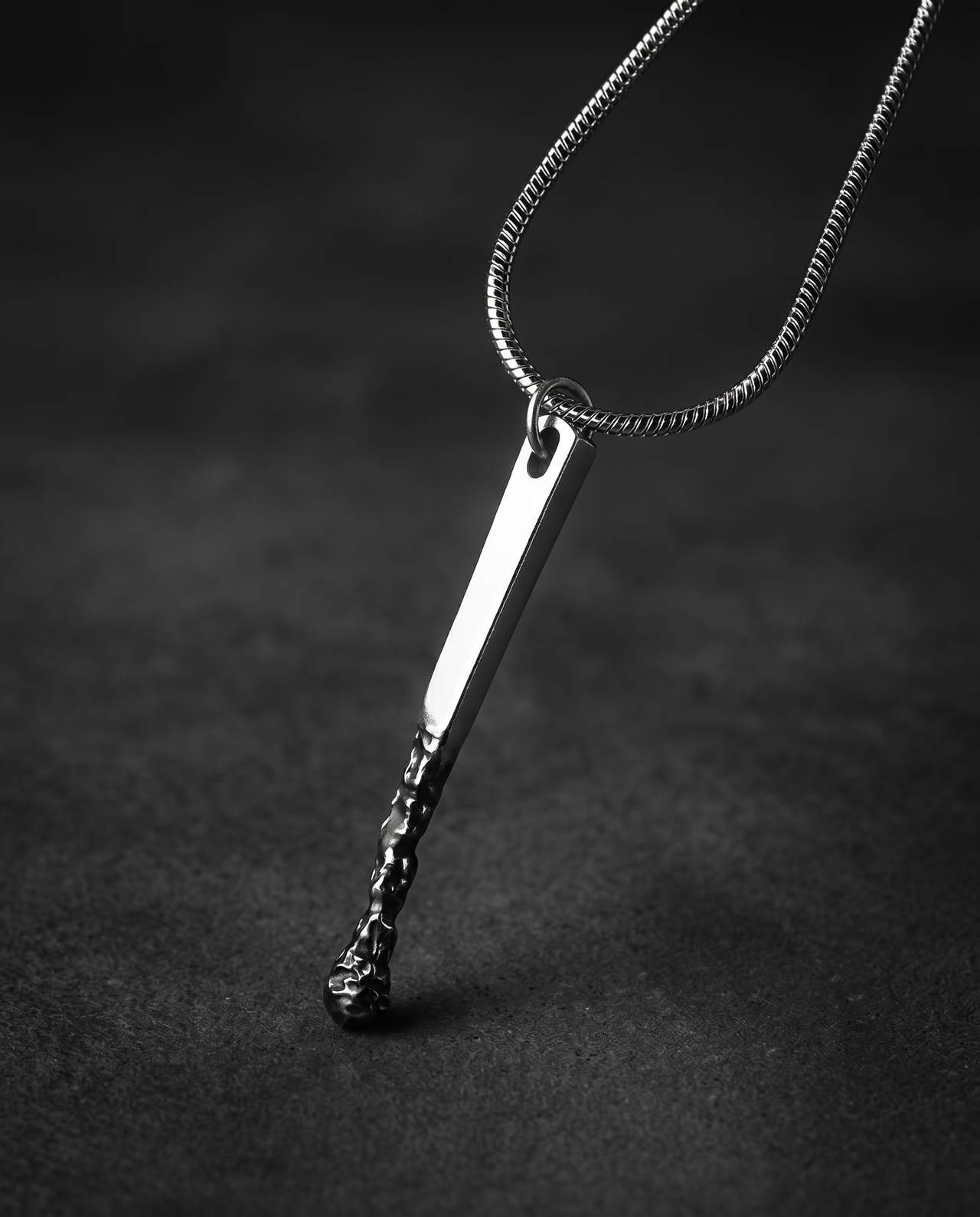 Silver pendant shaped like a burnt matchstick on a snake chain