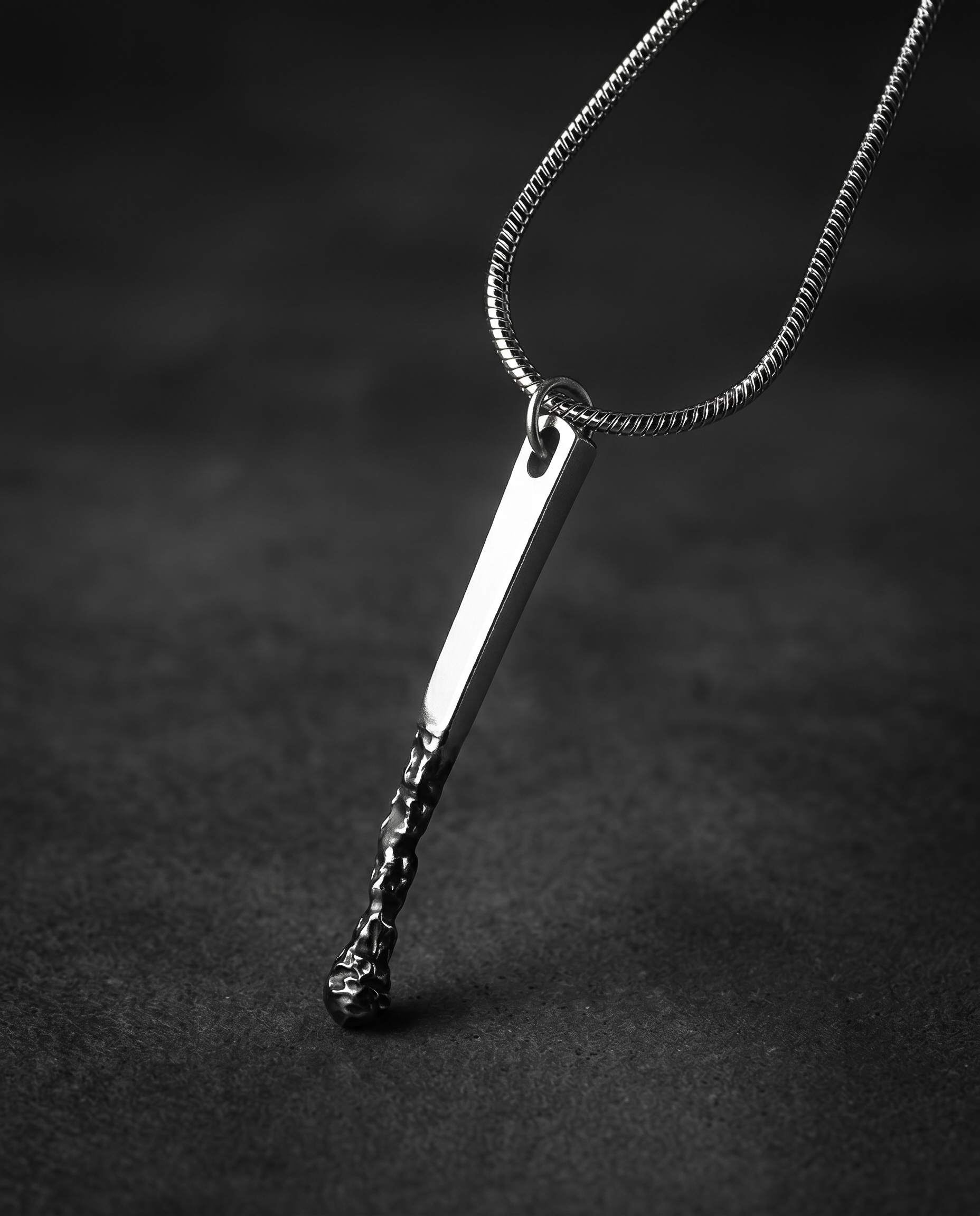 Silver pendant shaped like a burnt matchstick on a snake chain