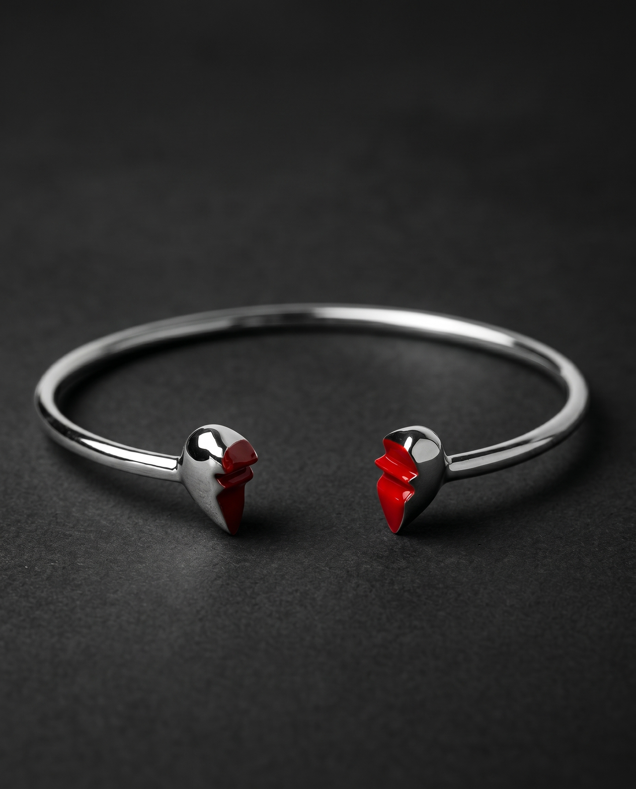 Silver open cuff bracelet ending in two red enamel heart halves