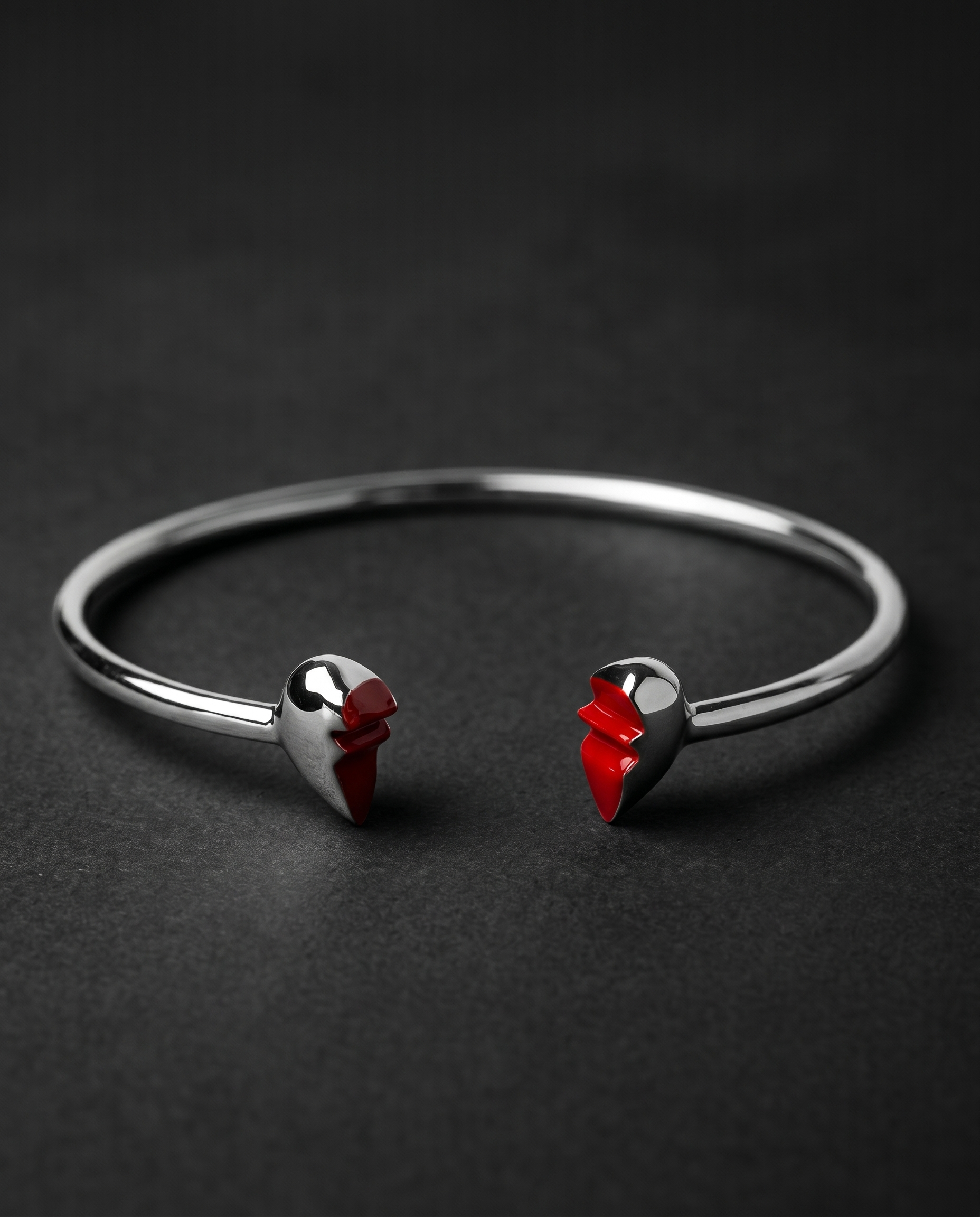 Silver open cuff bracelet ending in two red enamel heart halves