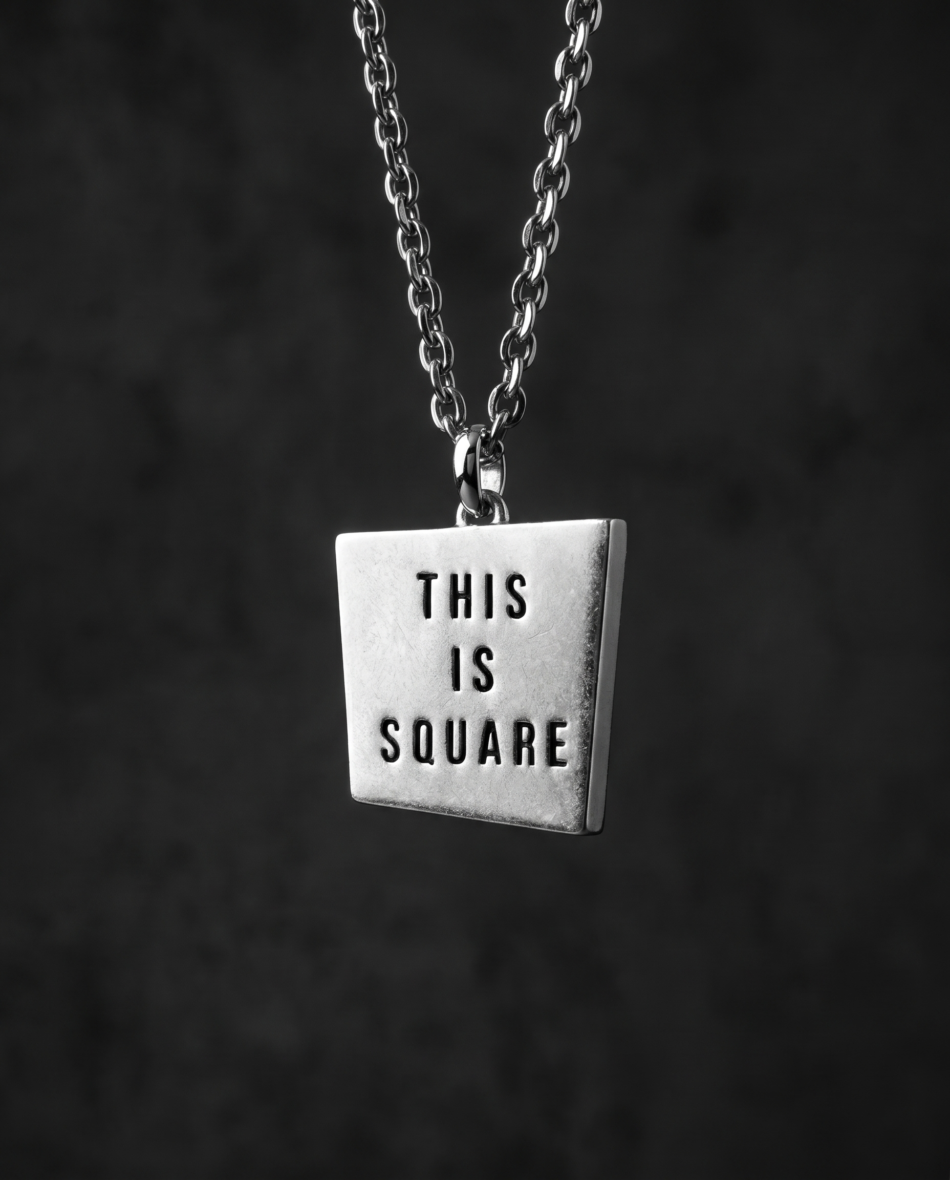 Matte silver square pendant engraved with THIS IS SQUARE on a chain