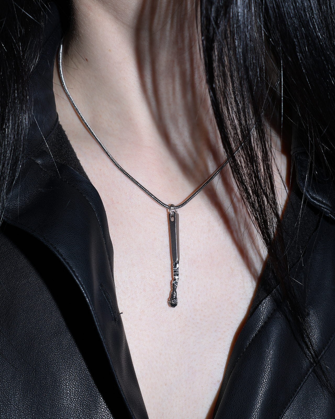 Silver pendant shaped like a burnt matchstick on a snake chain